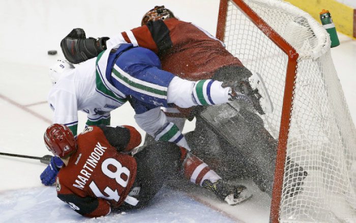 Arizona Coyotes’ left-wing Jordan Martinook (No. 48) and Vancouver Canucks’ right-wing Jack Skille (No. 9) crash into Coyotes’ goalie Mike Smith (R) during the second period of their NHL game in Glendale, Arizona, Thursday. - AP