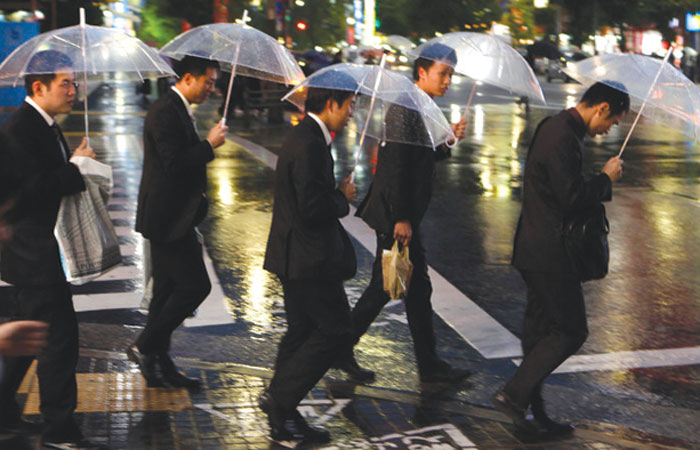 Japanese office goers cross a street in Tokyo. —  AP