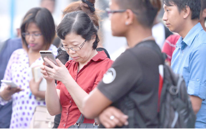 Chen Peijie, second left, China’s consul general in Sabah, checks her mobile phone at a jetty in Kota Kinabalu in the Malaysian Borneo state of Sabah on Sunday, as she awaits developments after a tourist boat carrying 28 Chinese nationals was reported missing on Saturday. — AFP