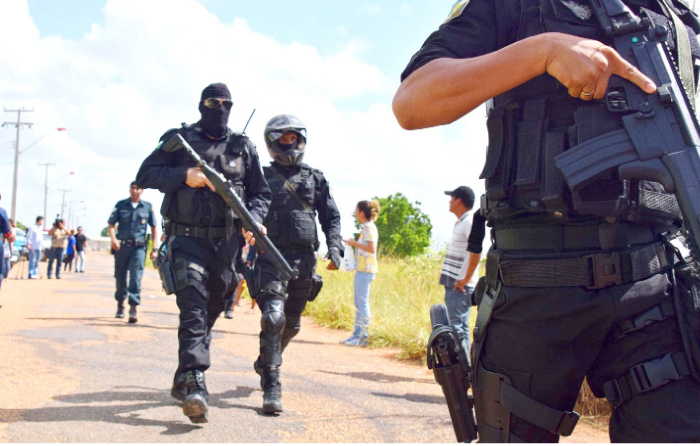 Heavily armed police officers walk outside the Agricultural Penitentiary of Monte Cristo, after  dozens of inmates were killed, in Boa Vista, Roraima state, Brazil, on Friday. — AP