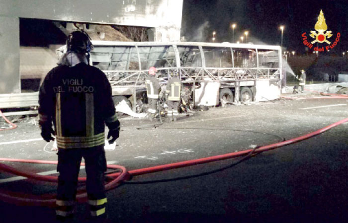 Firefighters extinguish flames in the wreckage of a bus following a crash on the A4 motorway near the Verona East exit, northern Italy, on Saturday. — AFP