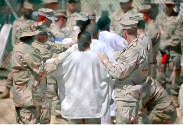 Guards stand on either side of a line-up of detainees to perform a search for unauthorized items at Guantanamo’s Camp 4 detention facility at Guantanamo Bay US Naval Base, Cuba, in this May 12, 2009 file photo. — AP