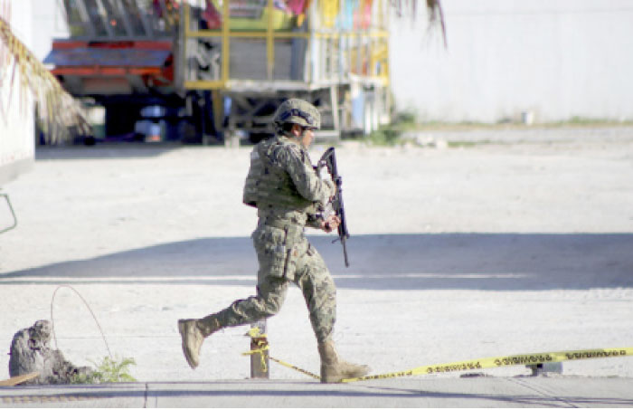 A soldier runs near the state prosecutor’s office after gunmen opened fire on the building in Cancun, Mexico, on Tuesday. — AP