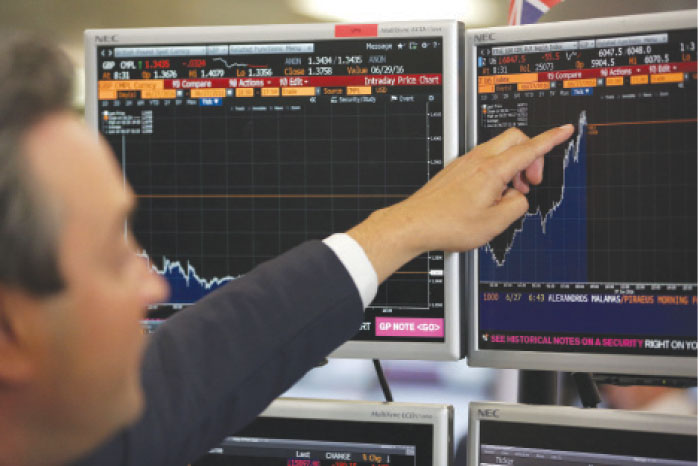 File photo shows a trader from ETX Capital pointing to a Bloomberg terminal showing the FTSE 100 index in central London. — AFP