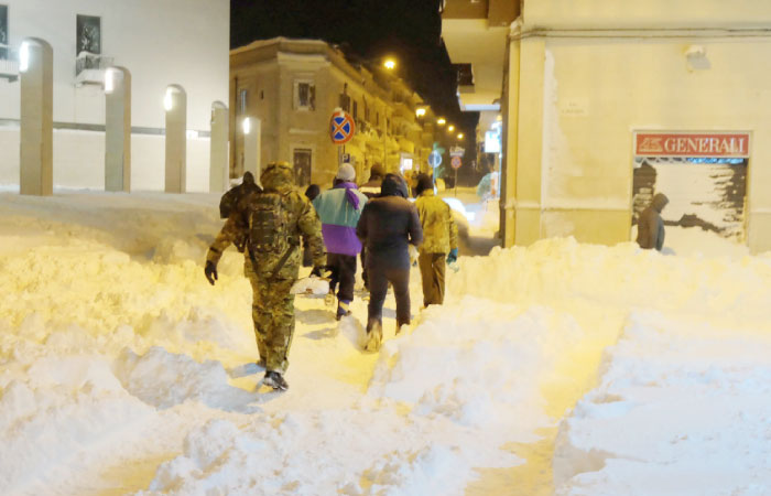 People walk in the snow in a street of Santeramo in Colle after snowfalls near Bari in the Puglia region in the south of Italy on Sunday. — AFP