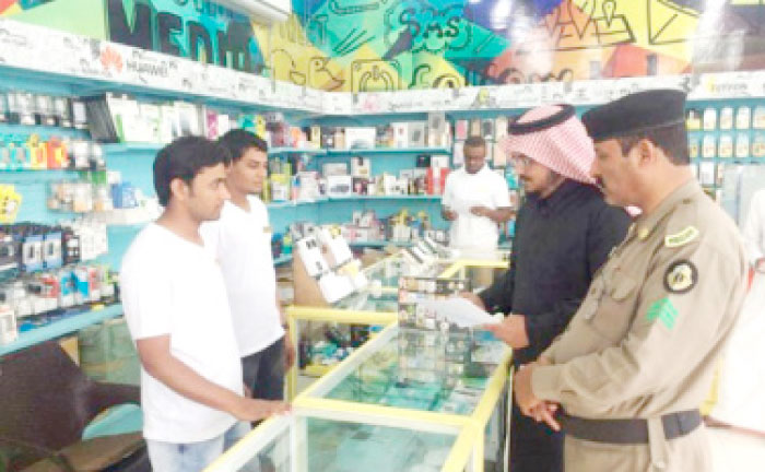 Inspectors check the documents of workers at a mobile phone shop in this file photo.