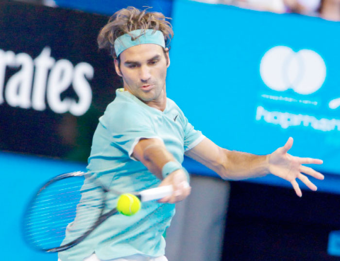 Roger Federer of Switzerland hits a return against Dan Evans of Britain during their men’s singles match at the Hopman Cup tennis tournament in Perth Monday. — AFP