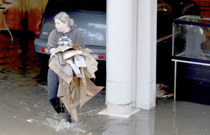 A woman at her family’s home in Carmel Valley, California, works to recover water-damaged items from a garage on Monday. — AP