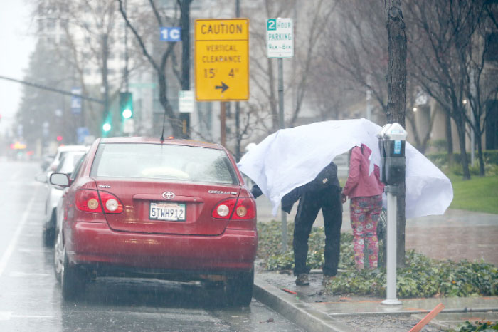 Two pedestrians lock up their vehicle before walking in the storm in San Jose, California, on Sunday. — AP