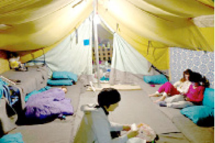 A Syrian refugee woman works inside her tent while her daughter left lies on the ground and her other daughter play with her friends, in Kalochori refugee camp on the outskirts of the northern Greek city of Thessaloniki in this Jan. 17, 2017 file photo. — AP