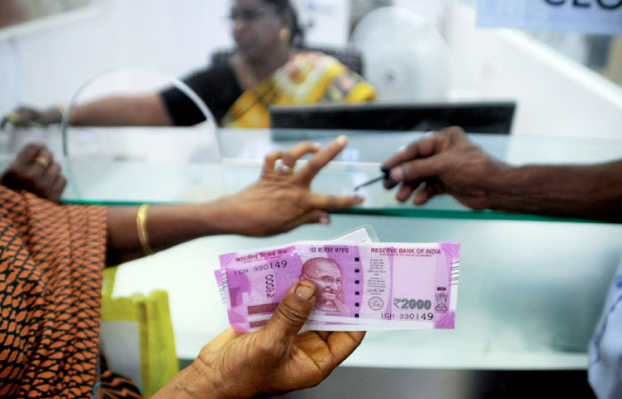 A file photo shows an Indian woman holds 2000 INR notes as she has her finger marked with indelible ink after exchanging 500 and 1000 INR banknotes at a bank in Chennai. — AFP