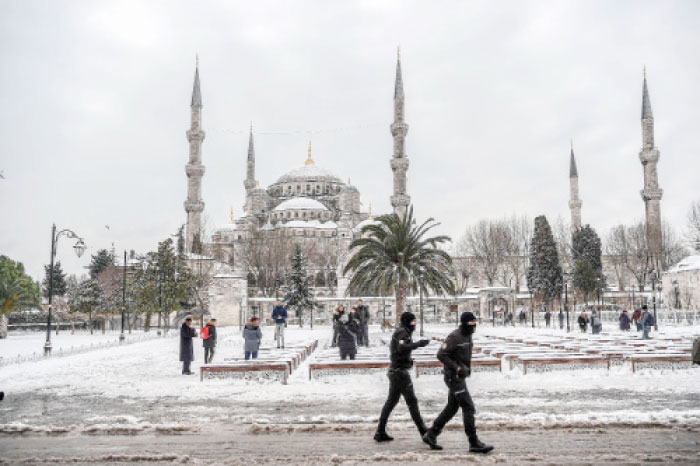 Turkish anti riot police officers patrol around the Blue mosque (Sultan Ahmet) during snowfall in Istanbul. — AFP