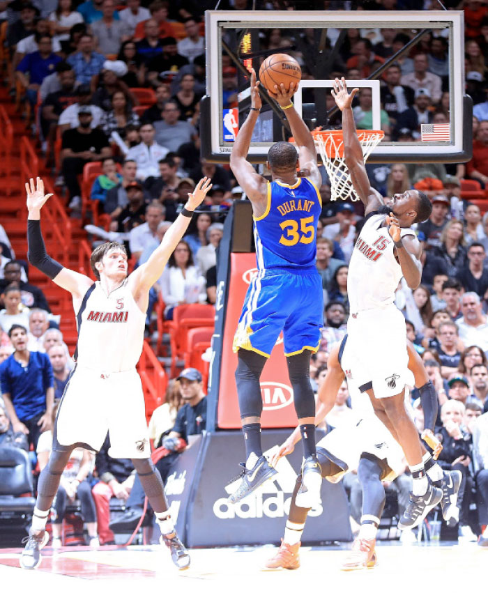 Kevin Durant (No. 35) of the Golden State Warriors shoots over Okaro White (No. 15) of the Miami Heat during a game at American Airlines Arena in Miami, Florida, Monday. - AFP