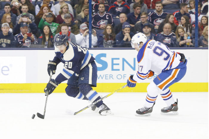 Columbus Blue Jackets’ left wing Brandon Saad (L) passes the puck past Edmonton Oilers’ center Connor McDavid during their NHL game at Nationwide Arena in Columbus Tuesday. — Reuters