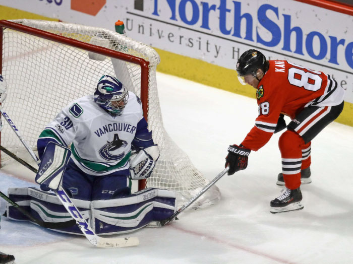 Patrick Kane (No. 88) of the Chicago Blackhawks tries to punch the puck under the leg pad of Ryan Miller (No. 30) of the Vancouver Canucks at the United Center in Chicago, Illinois, Sunday. - AFP