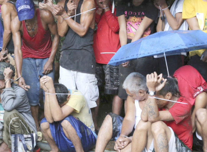 Filipino men are rounded up and have zip ties on their wrists following a police raid at an alleged drug den as part of the continuing “War on Drugs” campaign of Philippine President Rodrigo Duterte near the Payatas dumpsite community in suburban Quezon city, north of Manila, in this Oct. 5, 2016 file photo. — AP