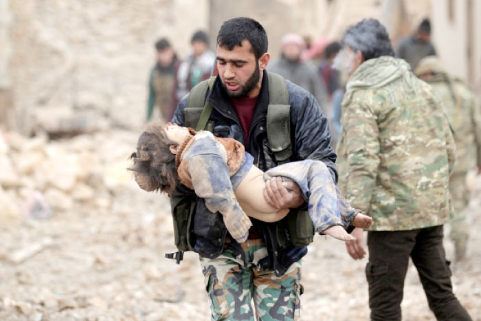 A rebel fighter carries an injured child after a car bomb explosion in Jub Al Barazi east of the northern Syrian town of Al-Bab. — Reuters