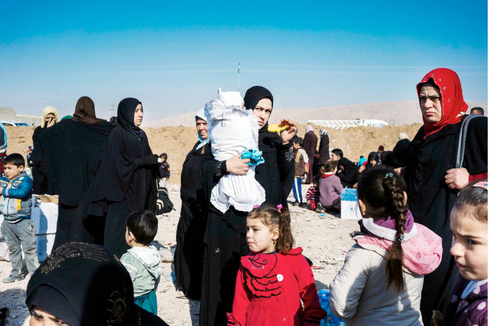 Displaced Iraqis, who fled the violence in the Daesh group stronghold of Mosul, wait for transportation to IDP camps near the town of Bartella. — AFP
