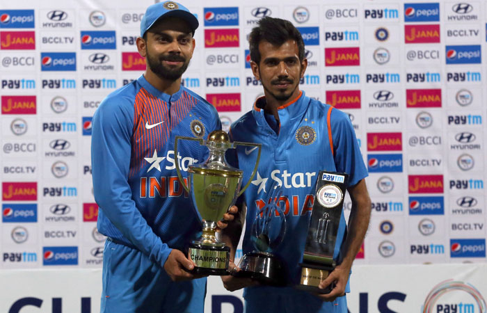 Indian cricket team captain Virat Kohli (L) and teammate Yuzvendra Chahal pose with the winners and Man of the Series trophies after their win over England in their third Twenty20 International match at Chinnaswamy Stadium in Bangalore Wednesday. — AP