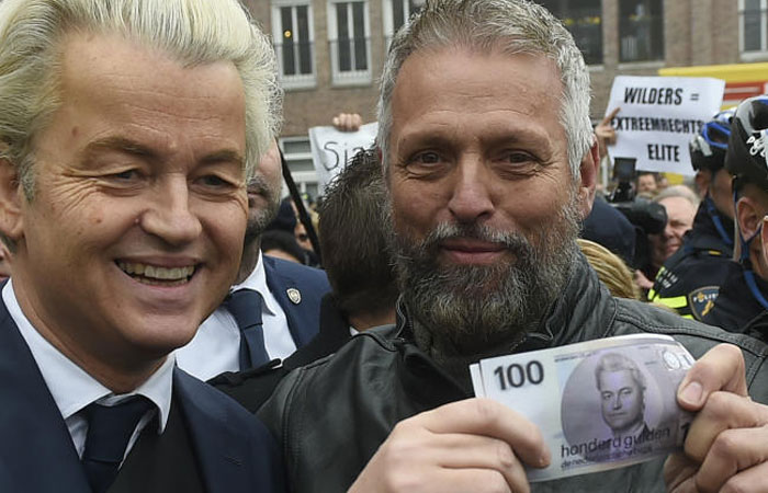 Dutch far-right politician Geert Wilders, left, poses for a photograph with a supporter holding a mock up of a Dutch Guilder banknote bearing his image, as he officially launches his parliamentary election campaign in Spijkenisse, the Netherlands, on Saturday. — AFP
