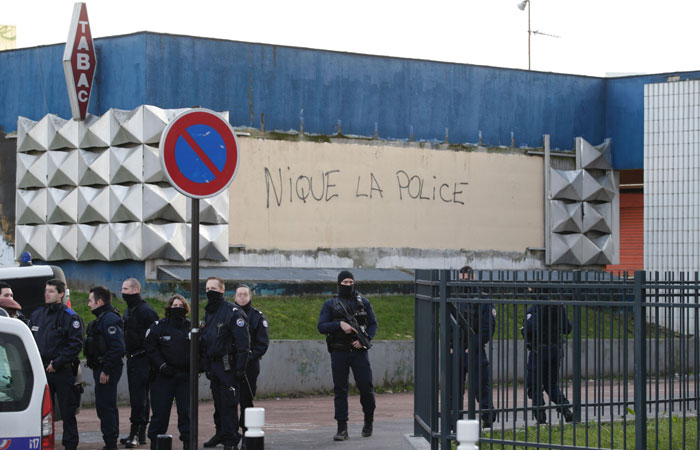 French policemen stand guard by a vandalized wall of the police station at the Rose des Vents district also known as the Cite des 3000 (City of 3000) in Aulnay-sous-Bois. Angry French youths clashed with police and burned cars in a Paris suburb for a third night in a row. — AFP