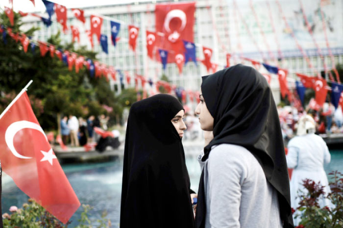 This file photo shows two young women in headscarves attending a pro-government rally outside the city hall in Istanbul. — AFP