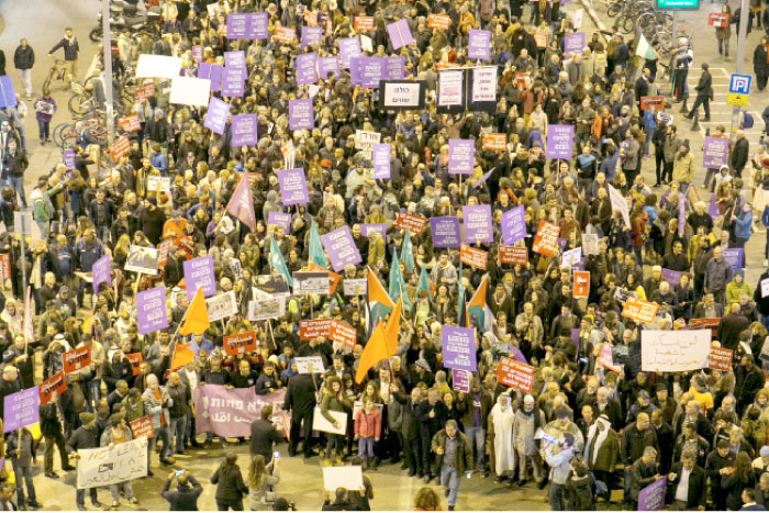 Left wing demonstrators hold signs during a protest against house demolitions in the Bedouin community in Tel Aviv. — Reuters