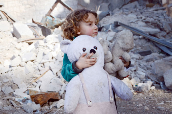 A Syrian girl, holding her stuffed toy, stands next to the rubble of buildings in the northwestern Syrian border town of Al-Bab. — AFP