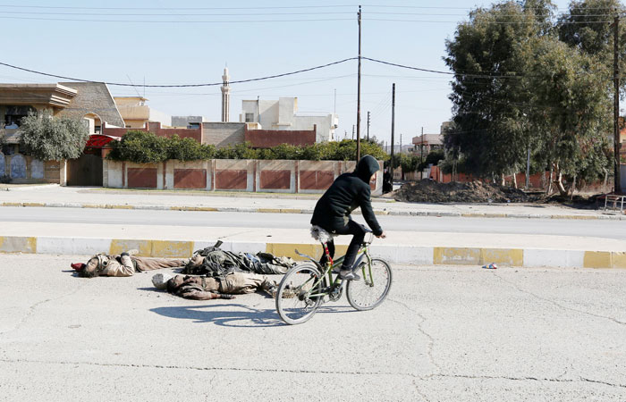 A boy rides a bicycle near the bodies of Daesh militants killed in clashes in Mosul. — Reuters