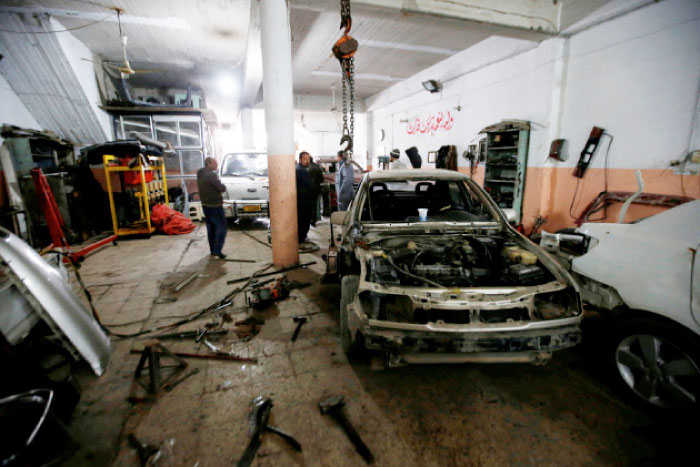 Workers fix cars at industrial neighborhood of Mosul. — Reuters