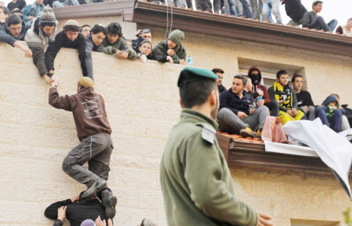 Israeli youths — the supporters of settlements — sit on a rooftop of a house which is due to be emptied and demolished in the settlement of Ofra in the occupied West Bank, during an operation by Israeli forces to evict the houses on Tuesday. — AFP