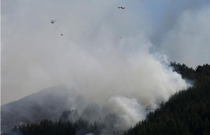 Two helicopters fight a wild fire in the Port Hills near Christchurch, New Zealand, on Tuesday. — AP