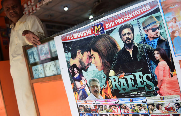 A Pakistani vendor stands alongside a poster of Indian Bollywood film 'Raees' at his shop in Karachi on Wednesday. Pakistan's ban on Bollywood thriller 