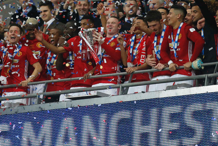 Captain Wayne Rooney lifts the trophy as Manchester United players celebrate their victory after the English League Cup final against Southampton at Wembley Stadium in north London Sunday. — AFP