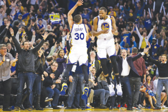 Golden State Warriors’ Stephen Curry (L) and Kevin Durant celebrate against the Los Angeles Clippers during their NBA game in Oakland Thursday. — AP