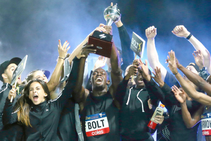 Jamaica’s Olympic champion Usain Bolt holds the trophy aloft as he celebrates with teammates during the final night of the Nitro Athletics series at the Lakeside Stadium in Melbourne Saturday. — Reuters