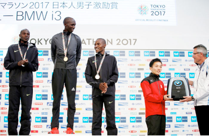 Tokyo Marathon silver medalist Gideon Kipketer (L) of Kenya, gold medalist Wilson Kipsang (2nd L) of Kenya and bronze medalist Dickson Chumba (C) of Kenya react to eighth place Hiroto Inoue (2nd R) of Japan receiving a mock key of BMW i3 as a prize for the best result for Japanese men on podium Sunday. — Reuters