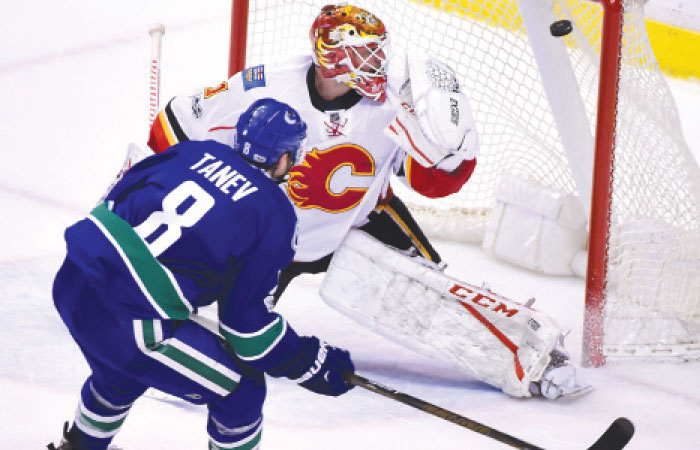 Vancouver Canucks’ defenseman Christopher Tanev scores a goal past Calgary Flames’ goaltender Brian Elliott during their NHL game at Rogers Arena in Vancouver Saturday. — Reuters