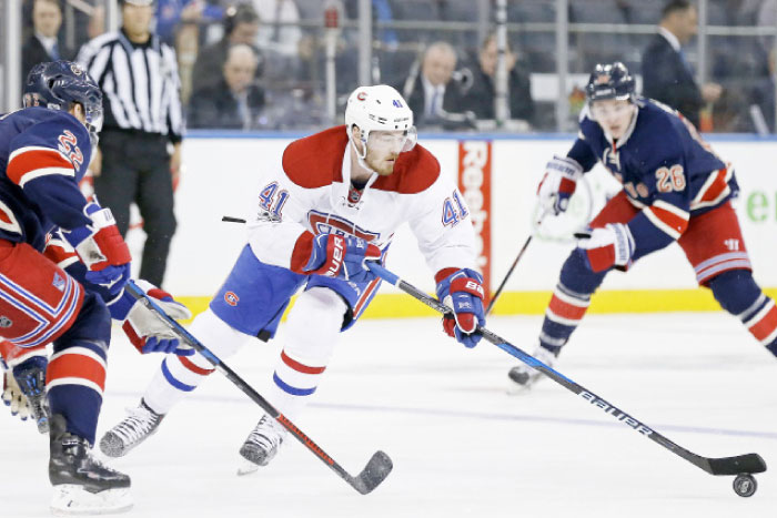 Montreal Canadiens’ left wing Paul Byron (C) controls the puck in front of New York Rangers’ defenseman Nick Holden (L) during their NHL game at Madison Square Garden in New York Tuesday. — Reuters