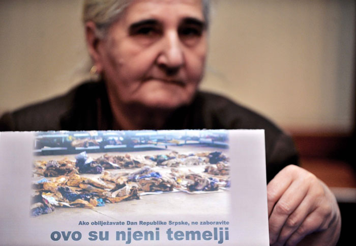 Bosnian Muslim woman Munira Subasic, survivor of 1995 massacre in Srebrenica, holds up a publication showing excavated remains of the Srebrenica massacre with caption 