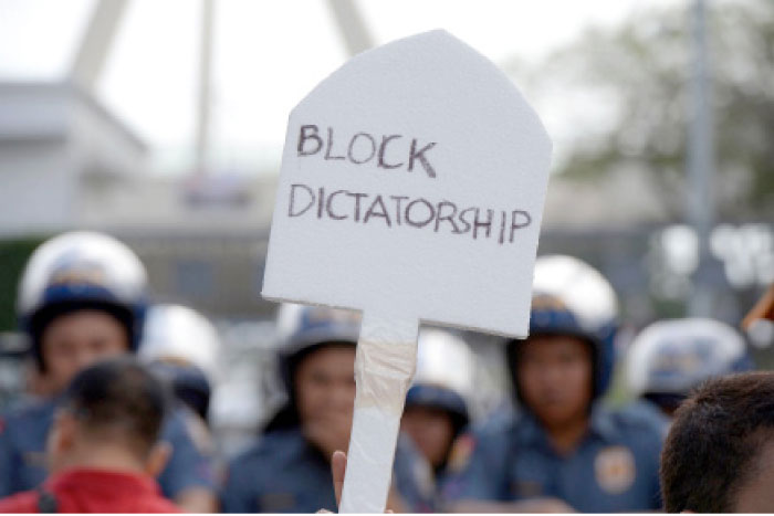 A protester displays an anti-Marcos slogan during a protest in front of the heroes’ cemetery in Manila on Saturday, to coincide with the anniversary of the “People Power” revolution. — AFP