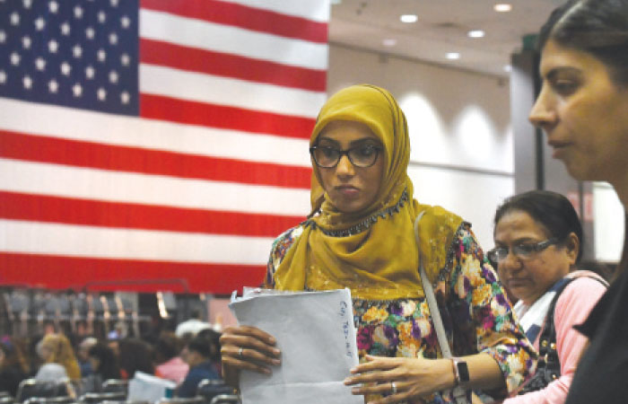 Saher Jangdah (center) picks up her certificate after pledging allegiance to the United States of America to become a US citizen, during a naturalization ceremony for immigrants in Los Angeles, California. Curbing immigration, as US President Donald Trump appears intent on doing, could slow already sluggish US economic growth as the flow of new workers from abroad has been an important factor in keeping the economy expanding. — AFP