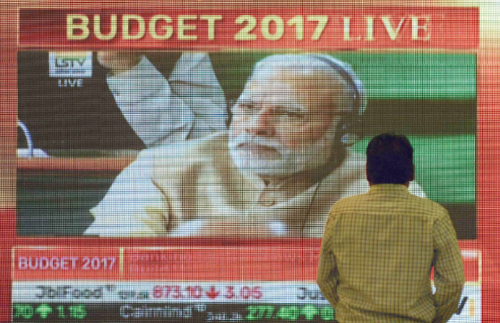 An Indian office-worker walks past a digital screen showing Indian Prime Minister Narendra Modi during Finance Minister Arun Jaitley delivering the budget speech at Parliament at the Bombay Stock Exchange (BSE) in Mumbai on Wednesday. — AFP