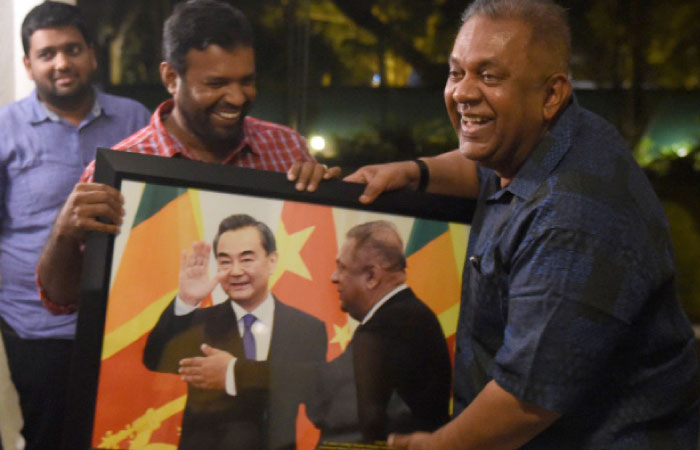 Sri Lanka’s Foreign Minister Mangala Samaraweera (R) accepts a framed photograph — taken by AFP photographer Ishara S. Kodikara — of himself with the visiting Chinese counterpart Wang Yi, from the Foreign Correspondents’ Association of Sri Lanka President Shiar Aneez (C) in Colombo. — AFP