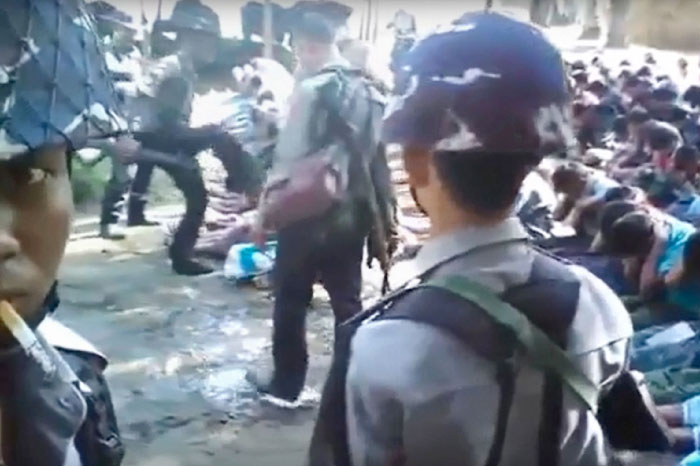 This file screen grab from a YouTube video originally taken by Myanmar Constable Zaw Myo Htike (pictured at far L - looking at camera) shows a policeman (back L) kicking out at a Rohingya minority villager seated on the ground with others, in the village of Kotankauk during a police area clearance operation on Nov. 5, 2016. Three police officers have been sentenced to two months detention over the video showing them abusing Rohingya civilians. — AFP