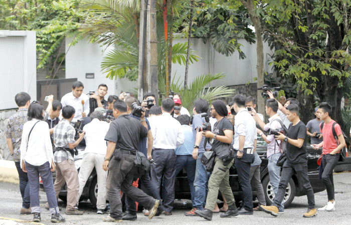 Journalists gather around a car leaving North Korean Embassy in Kuala Lumpur, Malaysia, on Monday. — AP