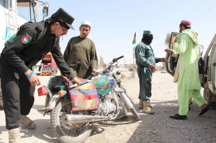 Afghan policemen search passengers at a checkpoint in Lashkar Gah in Helmand province on Tuesday. — AFP
