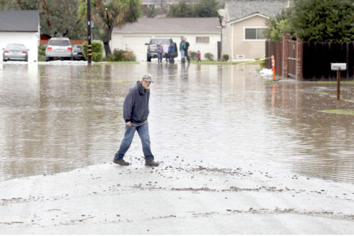A man walks on a flooded street in Salinas, California, on Monday. — AP