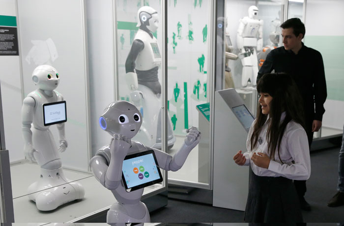Charllotte Abbot reacts to the movement of Pepper an interactive French-Japanese robot, during a press preview for the Robots exhibition held at the Science Museum in London, Tuesday. The exhibition which shows 500 years of mechanical and robotic advances is open to the public form Wednesday through to Sept. 3. — AP