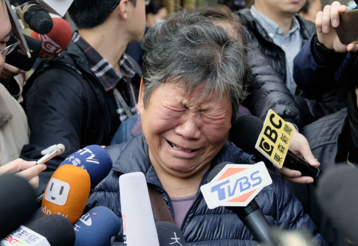 A relative of a victim of a bus crash cries while surrounded by members of the media the morning after the accident at a funeral home in Taipei on Tuesday. — AFP